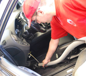 Photo of a man vacuuming the floor of a car.